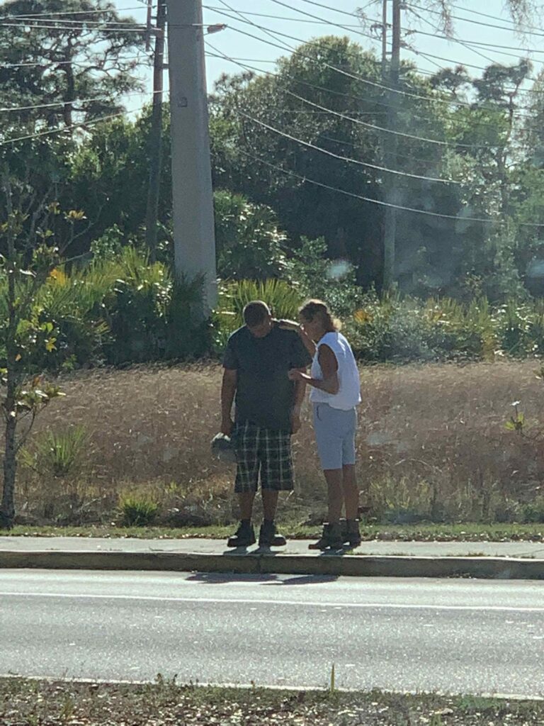 volunteer praying for homeless man during wellness check giving meals